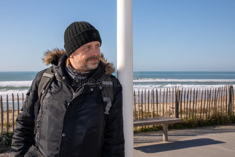 Handsome man happy smile in winter on ocean sand coast beach royalty free stock photo