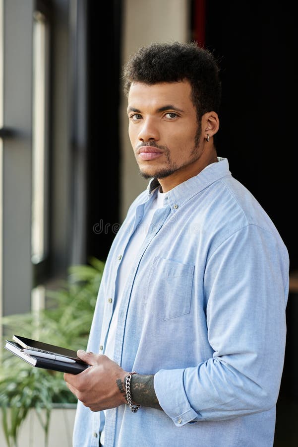 Handsome man holding notebook stands confidently stock photo