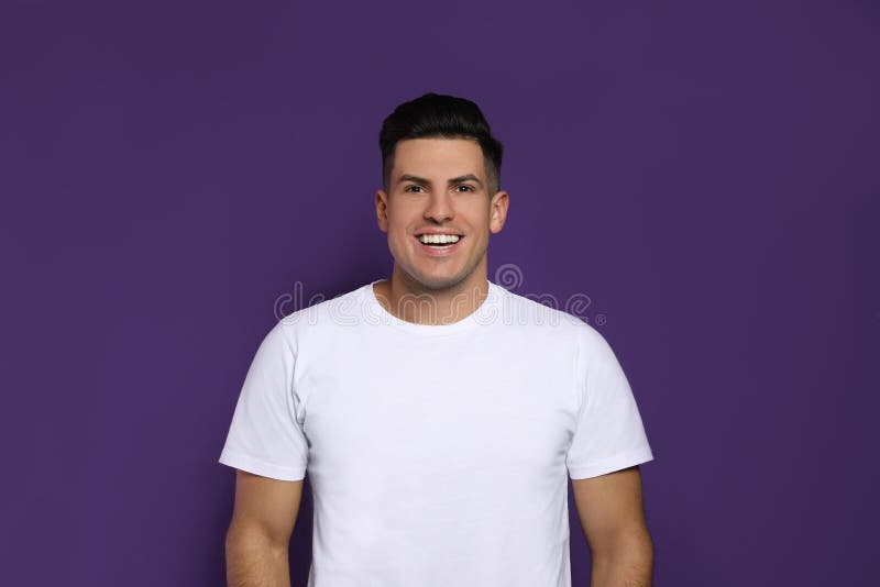 Handsome man laughing on purple background. Funny joke royalty free stock photo