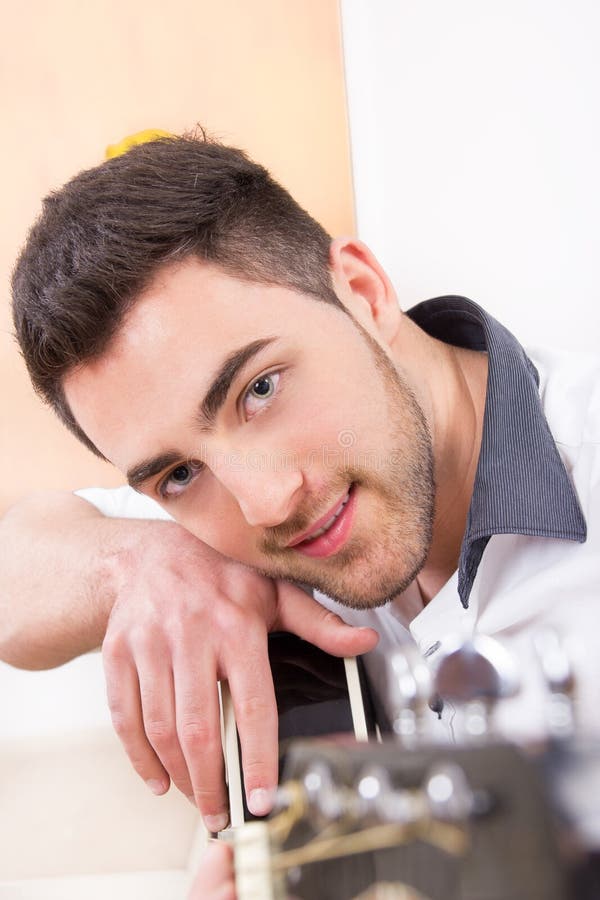 Handsome man leaning on his guitar and smiling stock photos Handsome man leaning on his guitar and smiling stock photos