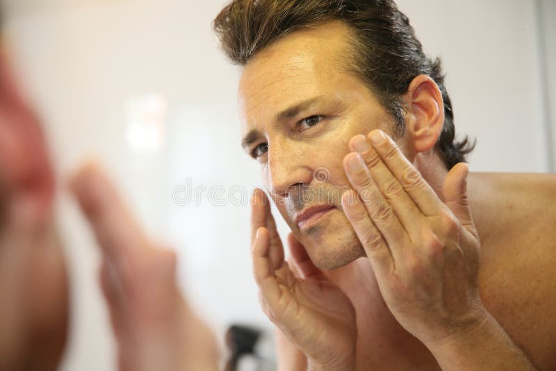 Middle-aged man in bathroom applying facial lotion. Problem wrinkle stock images, royalty-free photos and pictures