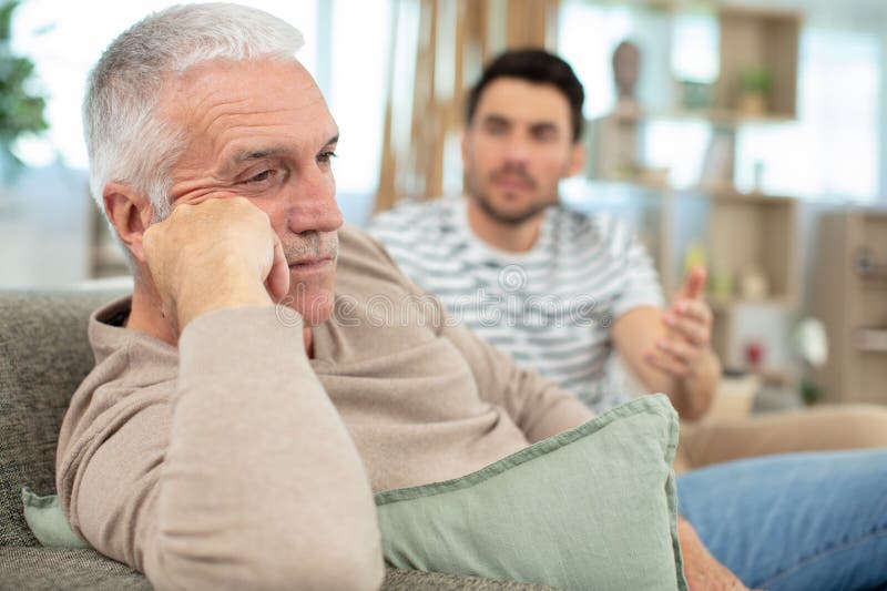 Handsome man looking at sad senior dad stock image