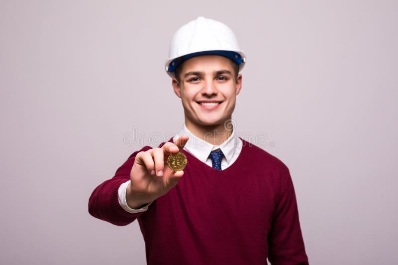 Handsome man miner with protective hamlet holds Bitcoin in his hand. Concept mining crypto currency of Bitcoin royalty free stock photo Handsome man miner with protective hamlet holds Bitcoin in his hand. Concept mining crypto currency of Bitcoin royalty free stock photo