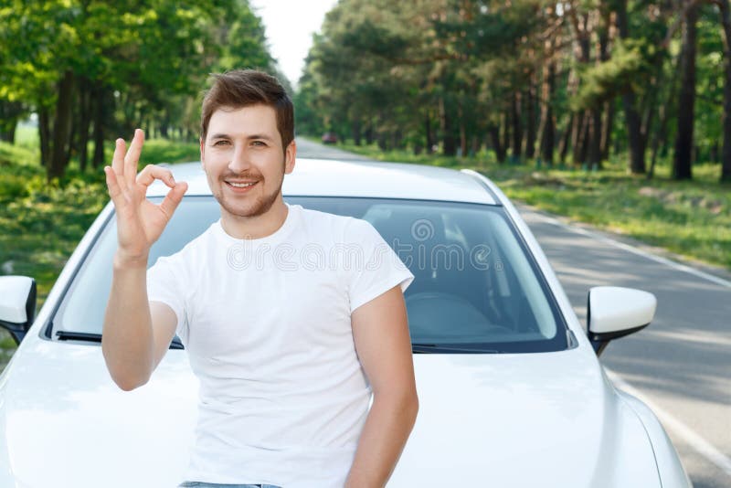 Handsome man pointing ok near car