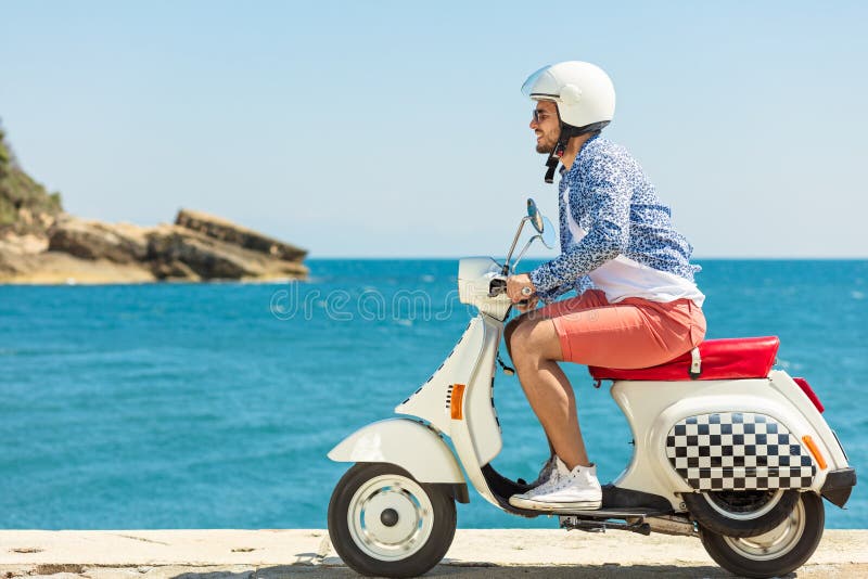 Handsome man posing on a scooter in a vacation context. Street fashion and style. royalty free stock photography Handsome man posing on a scooter in a vacation context. Street fashion and style. royalty free stock photography