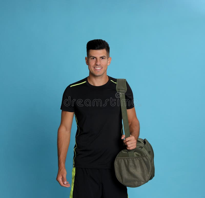 Handsome Man with Sports Bag on Light Blue Background Stock Photo