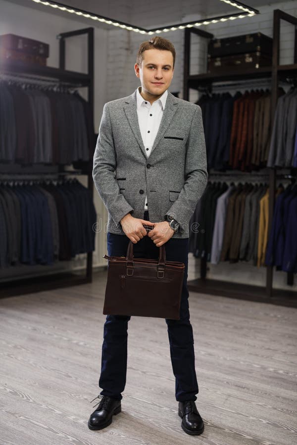 Handsome man stands in suit shop fashionable rich male dressed in expensive clothes posing indoors stock image Handsome man stands in suit shop fashionable rich male dressed in expensive clothes posing indoors stock image