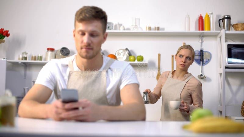 Handsome men typing message in phone, jealous wife peeping, cheating in marriage, stock photo. Handsome men typing message in phone, jealous wife peeping, cheating in marriage, stock photo