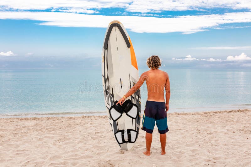 Handsome man walk with white blank surfing board wait for wave to surf spot at sea ocean shore. Concept of sport royalty free stock photos Handsome man walk with white blank surfing board wait for wave to surf spot at sea ocean shore. Concept of sport royalty free stock photos