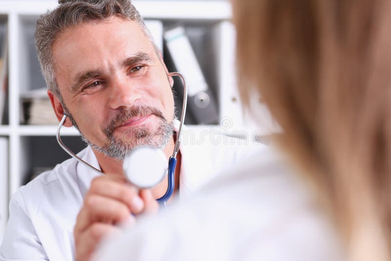 Handsome mature doctor hold in arm stethoscope head stock image Handsome mature doctor hold in arm stethoscope head stock image