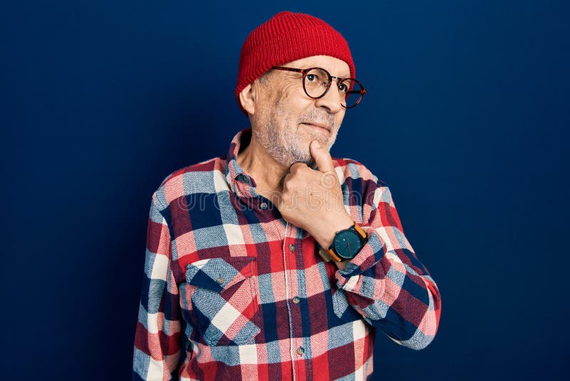 Handsome mature man wearing hipster look with wool cap with hand on chin thinking about question, pensive expression royalty free stock image