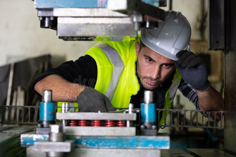 Mechanical engineer wearing protective helmet and gloves using wrench to fix the machine