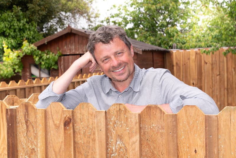 Handsome middle aged man leaning on wall wood outside the house