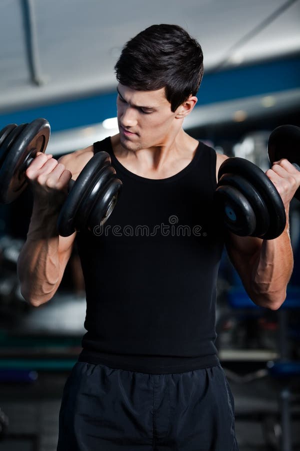 Handsome muscular man uses his dumbbells