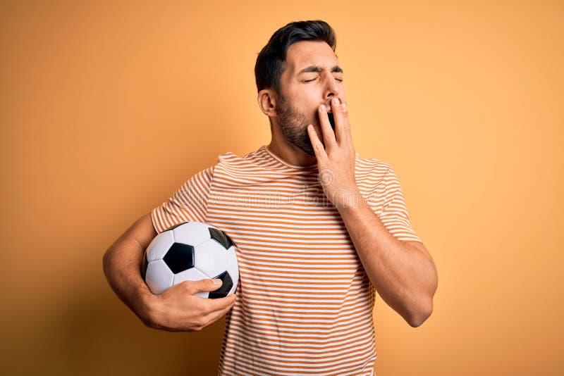 handsome-player-man-beard-playing-soccer-holding-footballl-ball-over-yellow-background-bored-yawning-tired-covering-mouth-212106353.jpg