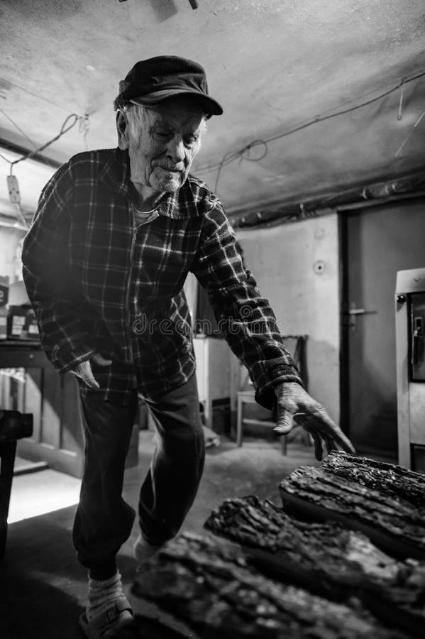 Handsome 80 plus year old senior man portrait. Black and white full body image of elderly man in boiler room, starting fire.