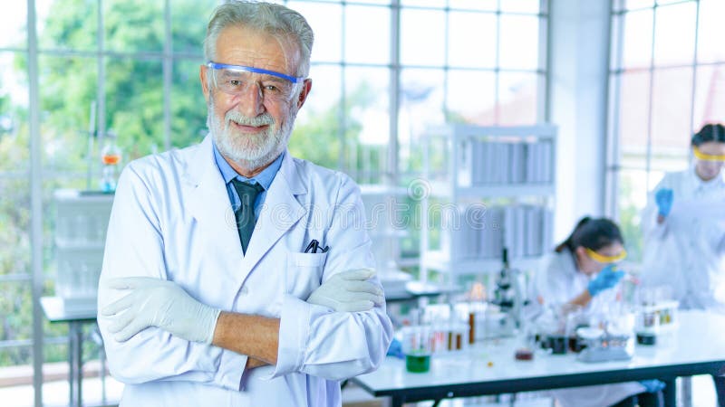 Handsome senior scientist man wearing white dress coat stand in front interior laboratory background smiling positive. Successful