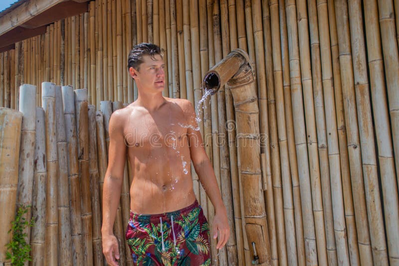 Handsome sexy boy in outdoors shower on the beach at the tropical island luxury resort in Maldives