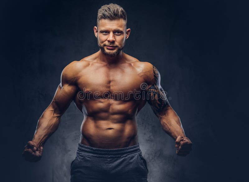 A Handsome Shirtless Tattooed Bodybuilder with Stylish Haircut and Beard,  Wearing Sports Shorts, Posing in a Studio Stock Image - Image of naked,  muscular: 114500855