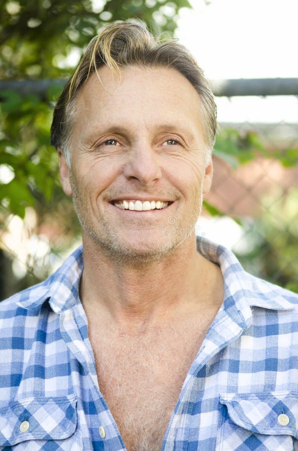 Handsome smiling mature blond man wearing a blue checked shirt and with