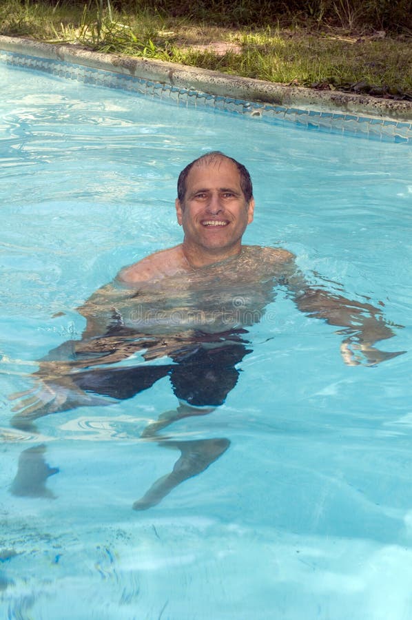 Handsome smiling middle age man swimming in pool