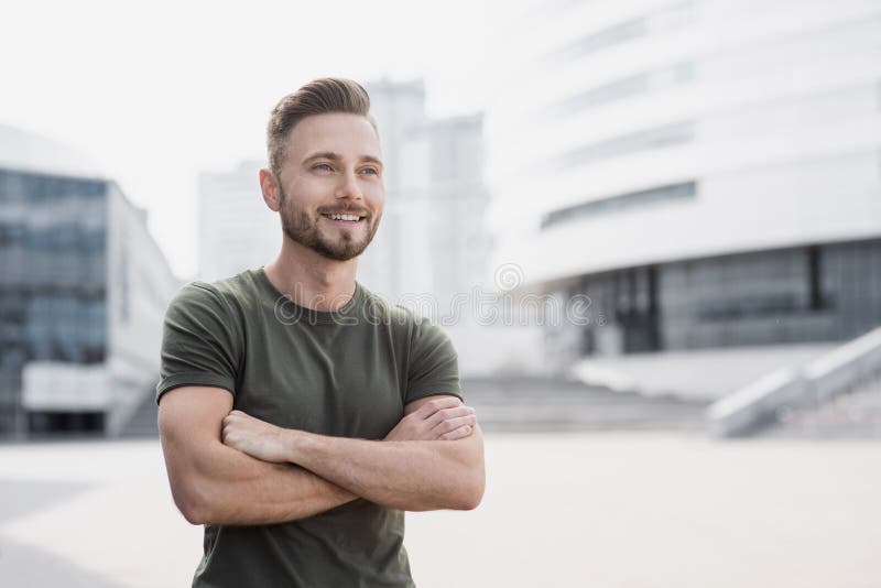 Handsome smiling young man with crossed arms looking up portrait.