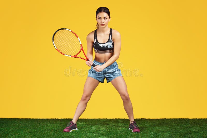 Handsome sporty young woman tennis player ready to shot the ball with red racquet over yellow background. stock images Handsome sporty young woman tennis player ready to shot the ball with red racquet over yellow background. stock images