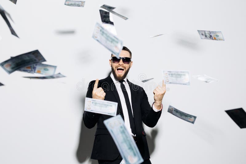 Handsome stylish business man in sunglasses and suit excited scream pointed up on fly money rain isolated on white background