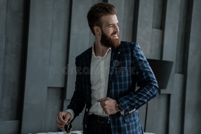 Handsome stylish man in blue suit in a cage smiling and looking away at home