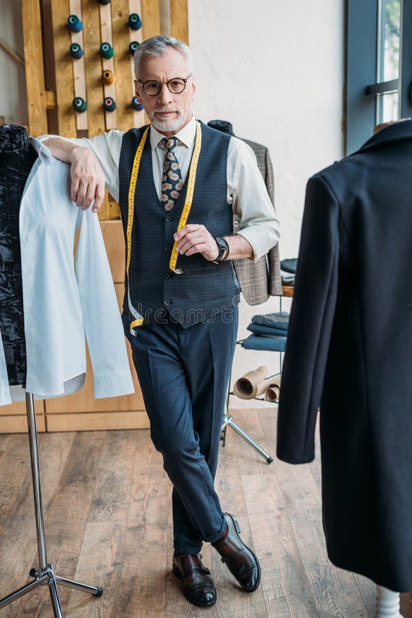 Handsome tailor leaning on mannequin stock photo