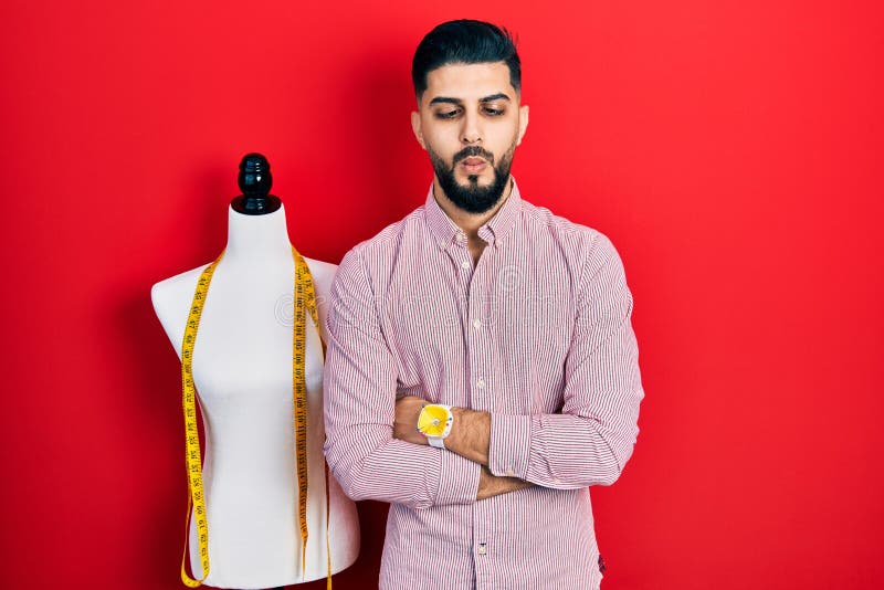 Handsome tailor man with beard with arms crossed gesture making fish face with mouth and squinting eyes, crazy and comical royalty free stock photo