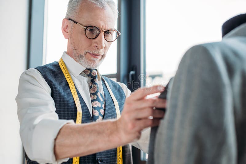 Handsome tailor touching jacket on mannequin royalty free stock photos