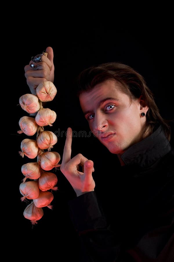Handsome vampire is not scared by garlic royalty free stock photo