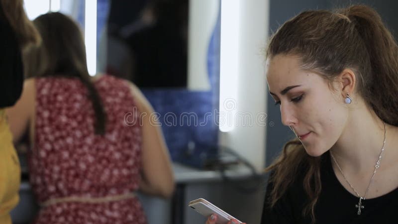 Handsome woman with high ponytail chats on cell phone in dressing room.