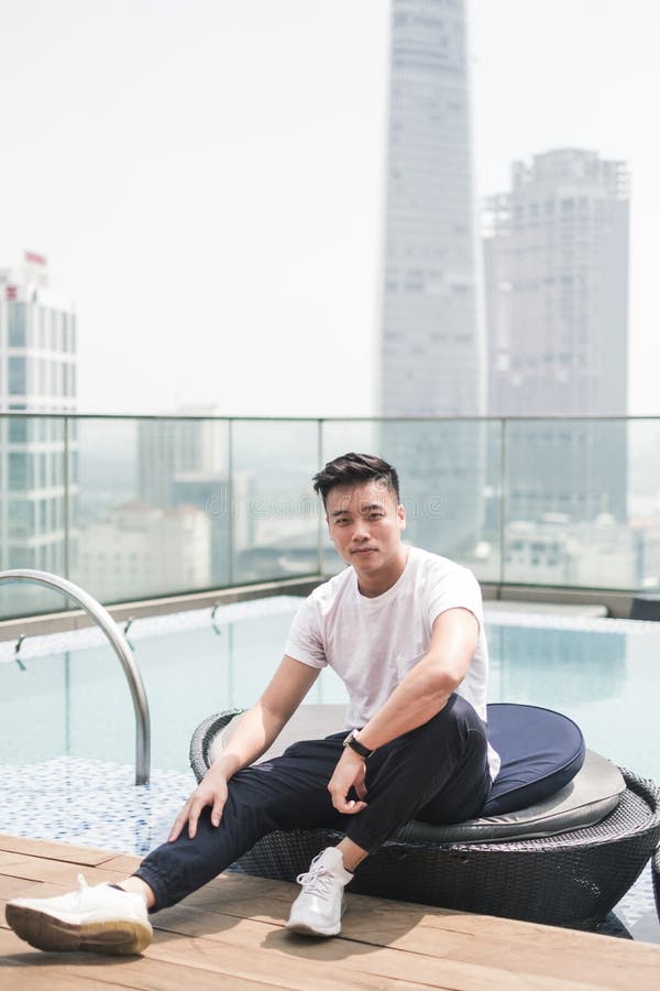 Handsome Young Asian Man Sitting on the Rooftop Near the Swimming Pool ...