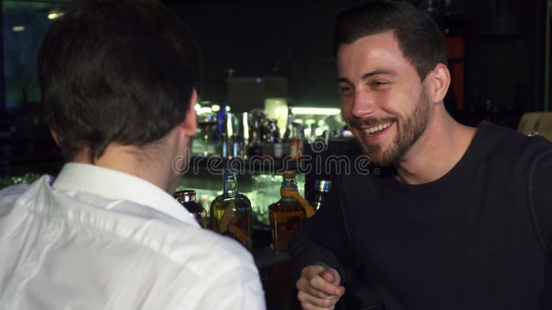 Young male friends talking while having drinks together at the bar stock image Young male friends talking while having drinks together at the bar stock image