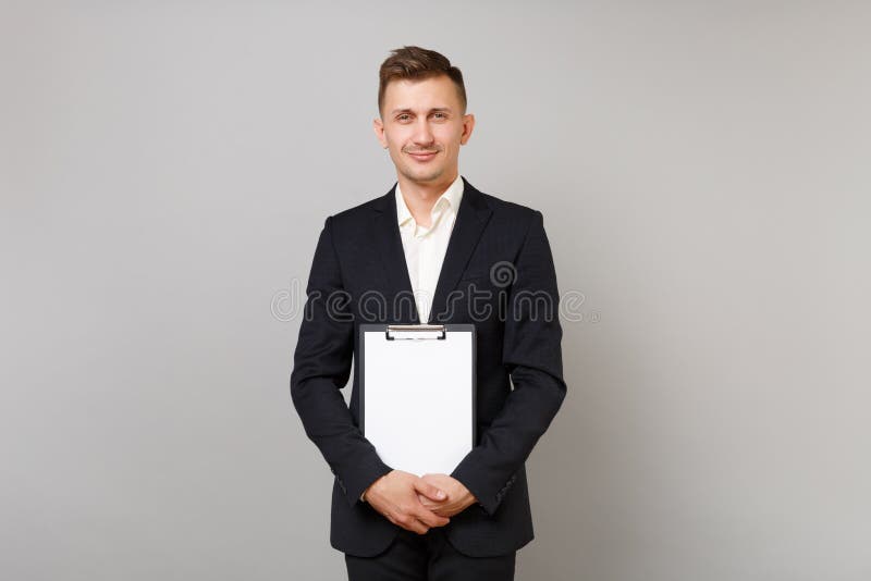 Handsome young business man in classic black suit, shirt holding clipboard with blank empty sheet workspace isolated on royalty free stock image Handsome young business man in classic black suit, shirt holding clipboard with blank empty sheet workspace isolated on royalty free stock image