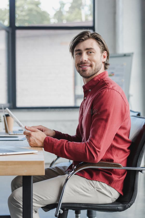 handsome young businessman using digital tablet and smiling at camera royalty free stock photos handsome young businessman using digital tablet and smiling at camera royalty free stock photos