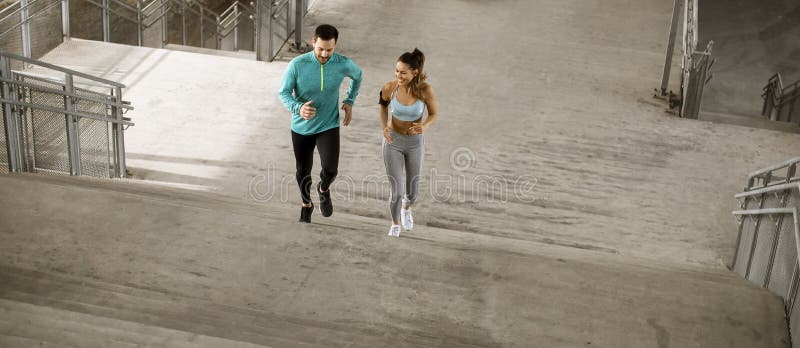 Young couple running in the urban environment stock photo