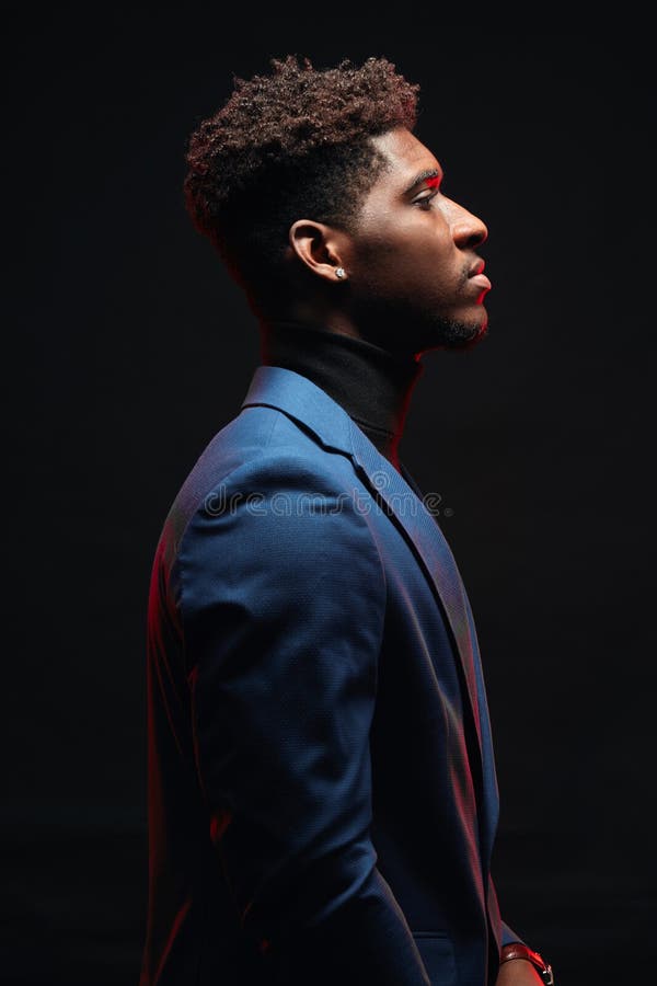 Handsome young dark-skinned male dressed in blue formal suit posing in profile royalty free stock image Handsome young dark-skinned male dressed in blue formal suit posing in profile royalty free stock image