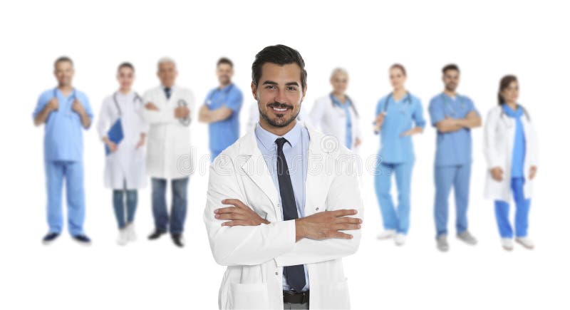 Handsome young doctor and blurred view of medical staff on white background. Banner design stock photo