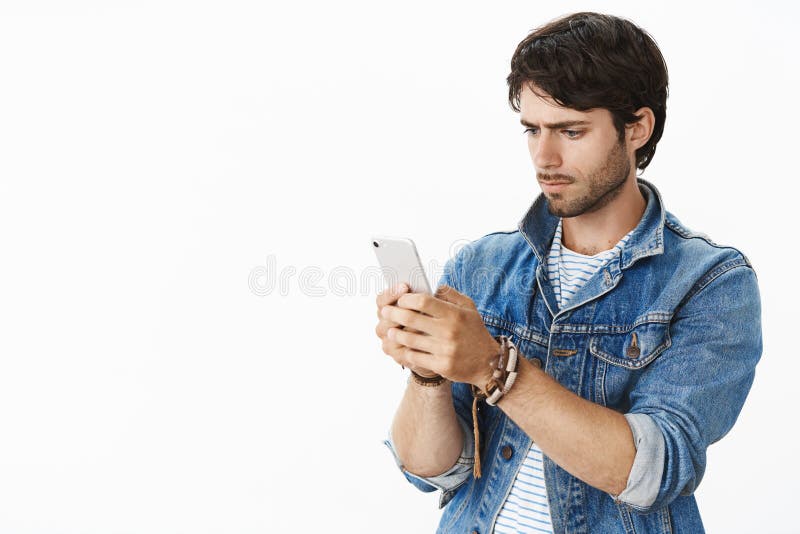 Handsome young guy stuggle catch wifi as trying contact friend standing perplexed and serious over gray background in