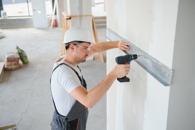 Handsome young male builder in hard hat, while working at construction site. royalty free stock image