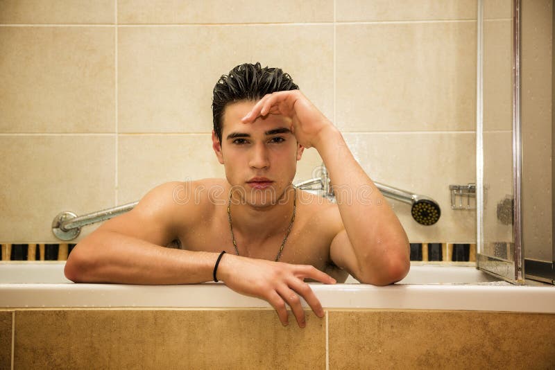 Pěkný mladý muž v vana na s koupel, tělo a vlasy a šampon.