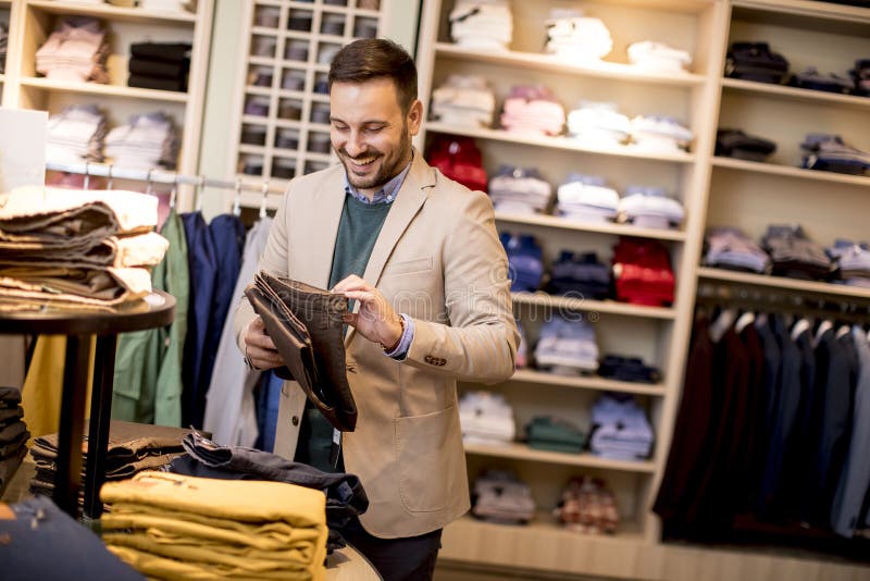Handsome young man buying trousers in fashion store royalty free stock photography Handsome young man buying trousers in fashion store royalty free stock photography
