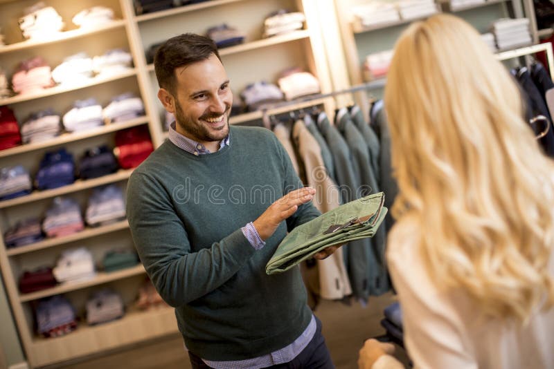 Handsome young man buying trousers with his wife in fashion store royalty free stock photo