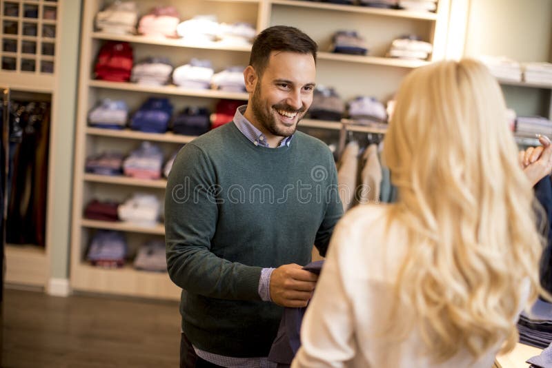 Handsome young man buying trousers with his wife in fashion store royalty free stock photo