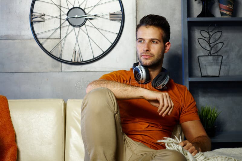 Handsome young man daydreaming at home stock photo