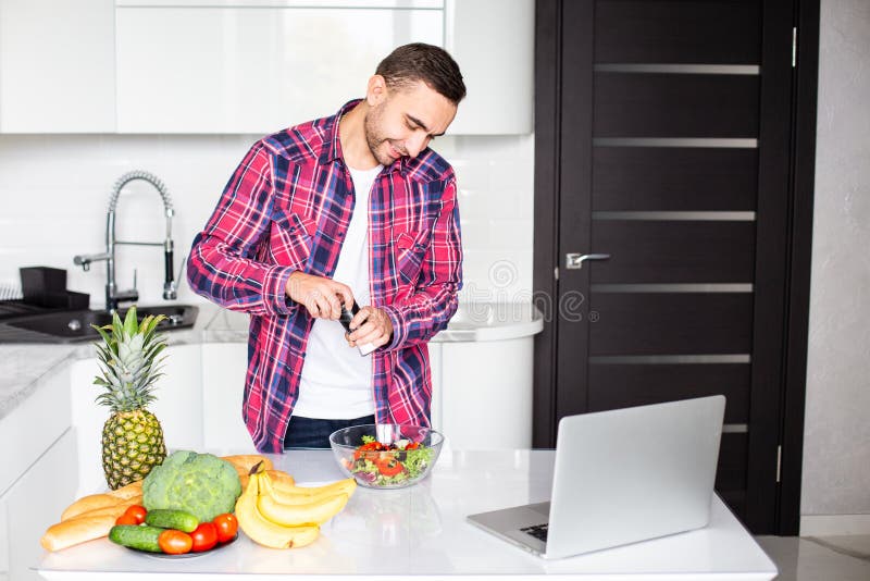 Enjoying cooking time. Handsome young man enjoying cooking time in his spacious modern kitchen stock images