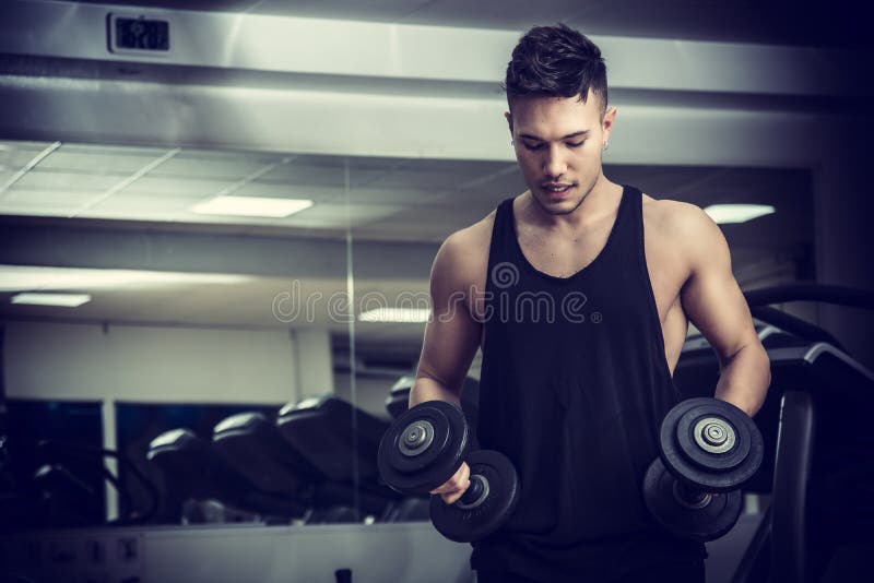 Handsome young man exercising biceps in gym